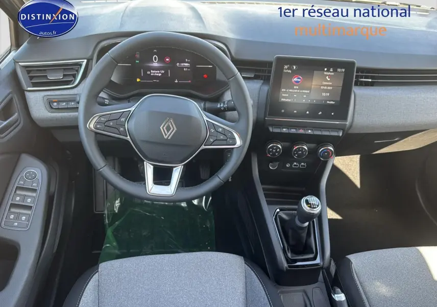 Vue intérieure de la Renault Clio 2025 montrant le volant, tableau de bord numérique et levier de vitesse manuel.