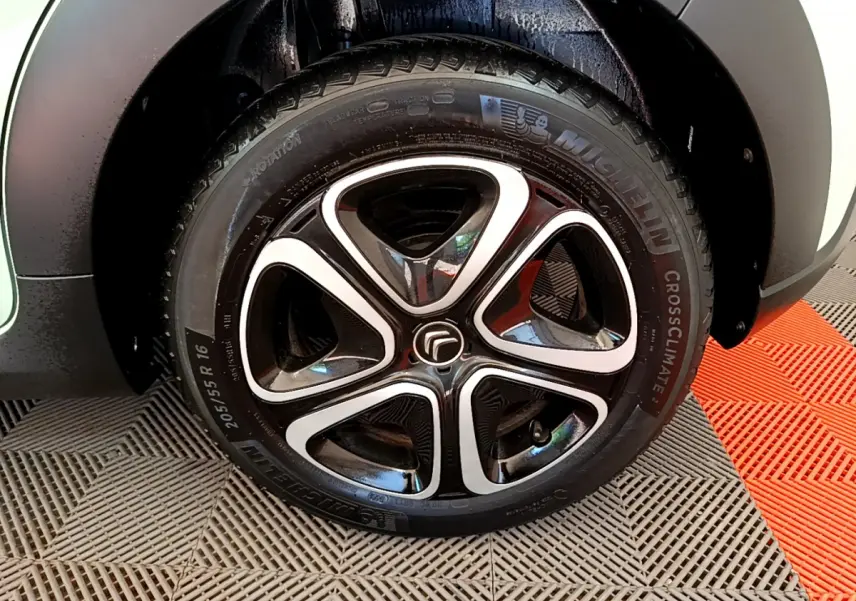 Gros plan sur la roue avant gauche de la Citroën C3 PureTech 82 S&S BVM Graphic verte avec jante alliage noire et argentée.