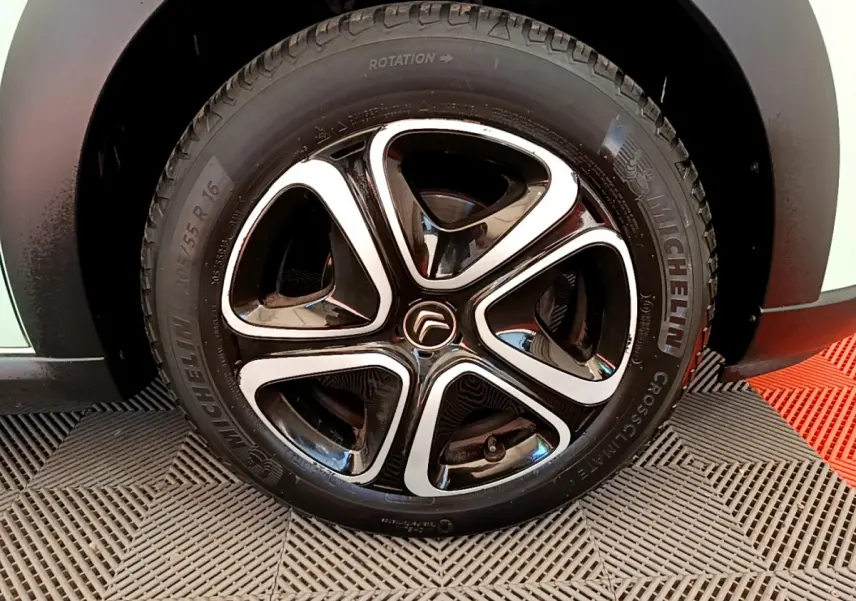 Gros plan sur la jante noire et argentée d'une Citroën C3 PureTech 82 verte, avec pneu Michelin visible.