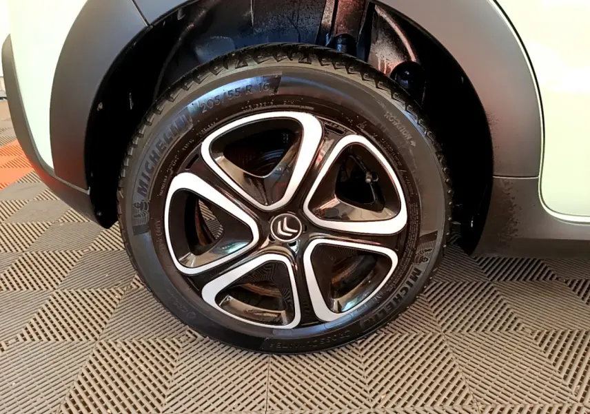 Gros plan sur la roue avant gauche d'une Citroën C3 vert clair, mettant en valeur la jante noire et argentée au design moderne.