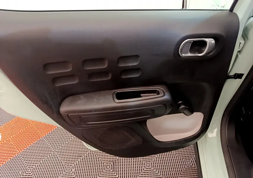 Gros plan sur la porte avant gauche vert clair d'une Citroën C3 2019 avec poignée noire et manivelle de vitre.
