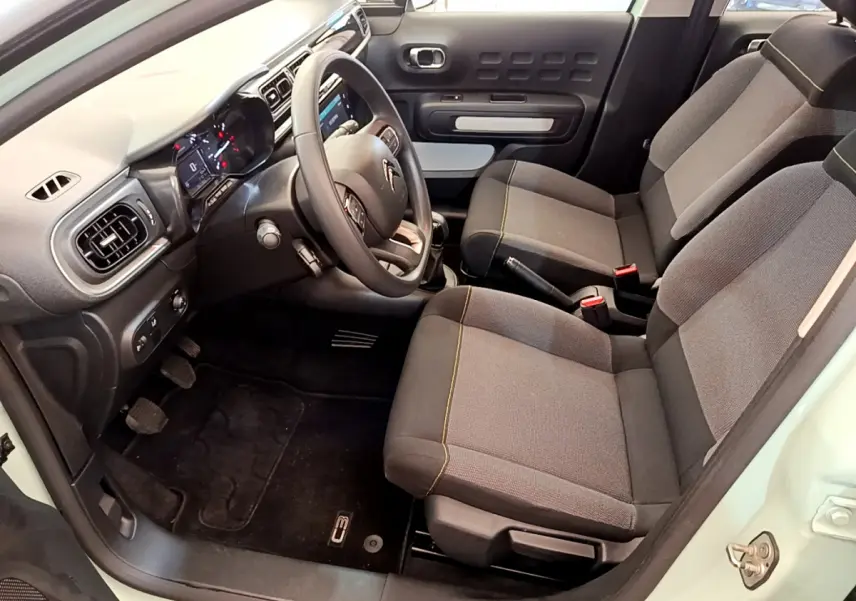 Intérieur avant droit de la Citroën C3 PureTech 82 vert 2019, montrant sièges tissu gris et tableau de bord moderne.