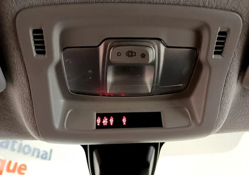 Vue intérieure du plafonnier avec éclairage et témoins de ceintures allumés dans une Citroën C3 verte 2019.