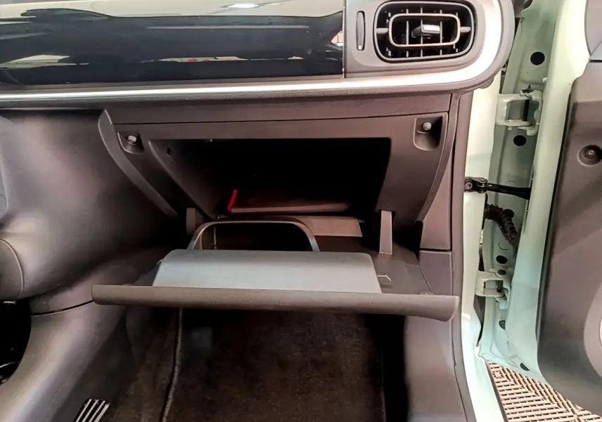 Vue intérieure côté passager du coffre à gants ouvert d'une Citroën C3 2019 vert clair avec tableau de bord noir brillant.