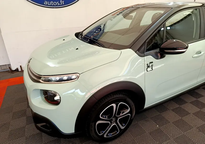 Vue 3/4 avant gauche d'une Citroën C3 PureTech 82 vert clair avec jantes noires et logo C3 sur l'aile.