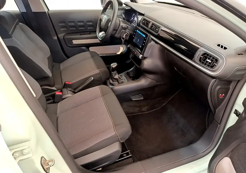 Intérieur avant droit d'une Citroën C3 vert clair 2019 avec tableau de bord noir et écran tactile central.