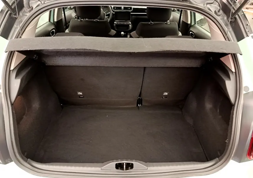 Coffre ouvert vu de l'arrière d'une Citroën C3 vert 2019 avec tablette cache-bagages et sièges arrière noirs.