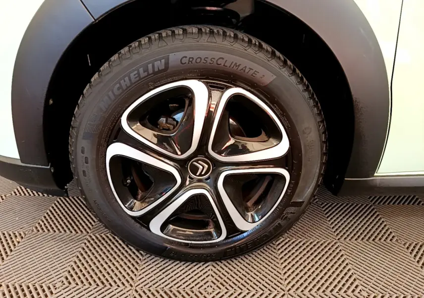 Gros plan sur la roue avant droite d'une Citroën C3 verte avec jante noire et argentée au design moderne.