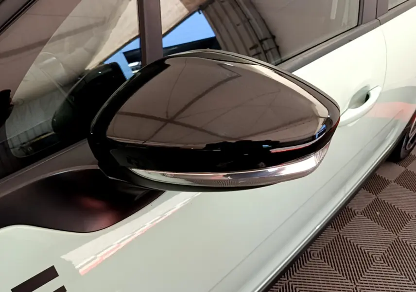 Rétroviseur côté gauche noir brillant avec clignotant intégré sur Citroën C3 vert vue rapprochée du côté conducteur.