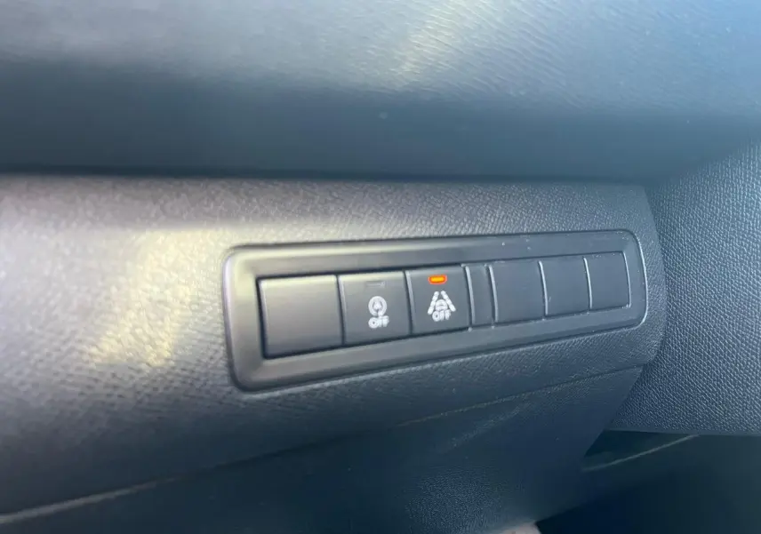 Boutons de commande d'assistance à la conduite sur tableau de bord noir d'une Peugeot 308 SW gris clair.