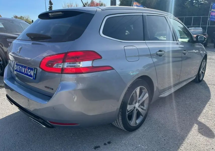 Peugeot 308 SW gris clair vue 3/4 arrière droit, avec vitres surteintées et jantes alliage 17 pouces diamantées.