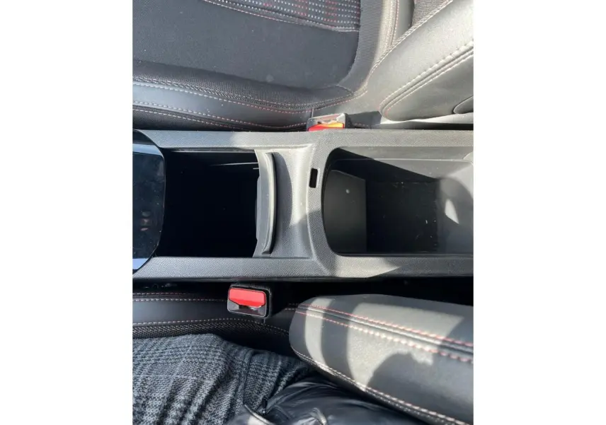 Gros plan sur la console centrale noire avec surpiqûres rouges et sièges en tissu gris foncé de la Peugeot 308 SW GT Line.