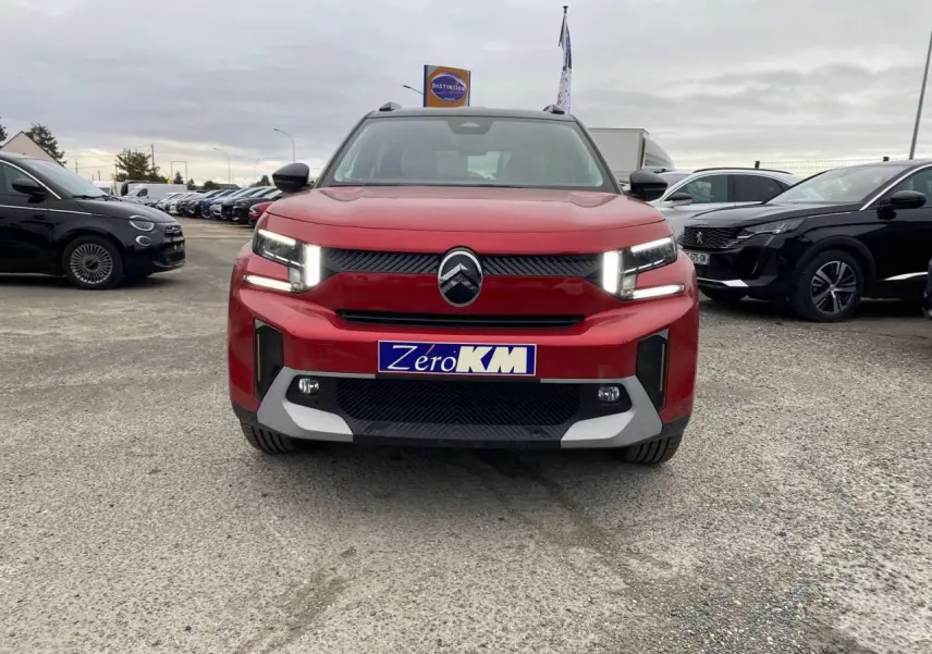 Vue frontale d'un Citroën C3 Aircross rouge Elixir avec toit noir, feux LED allumés sur parking extérieur.