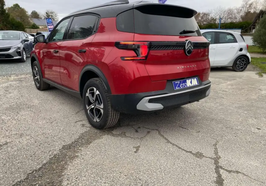 Vue 3/4 arrière droite du Citroën C3 Aircross rouge Elixir avec toit noir et feux arrière LED 3D sur parking.
