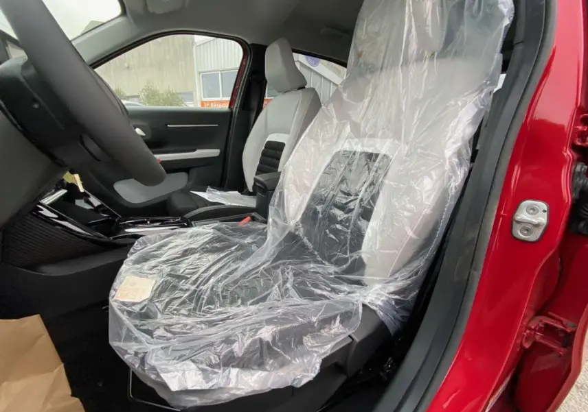 Vue intérieure côté conducteur du Citroën C3 Aircross 2025 rouge Elixir, siège avant protégé par housse plastique.