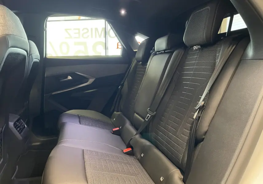 Vue latérale droite de la banquette arrière en tissu noir du Peugeot 3008 Hybrid 2025 avec ceintures et appuie-têtes.