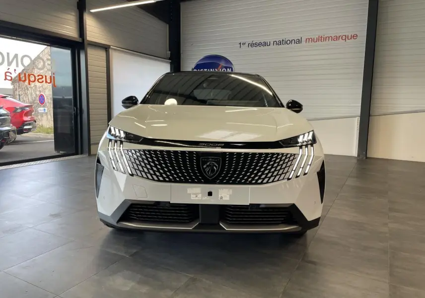 Vue frontale d'un Peugeot 3008 blanc Okenite avec calandre moderne et feux LED griffés en showroom.