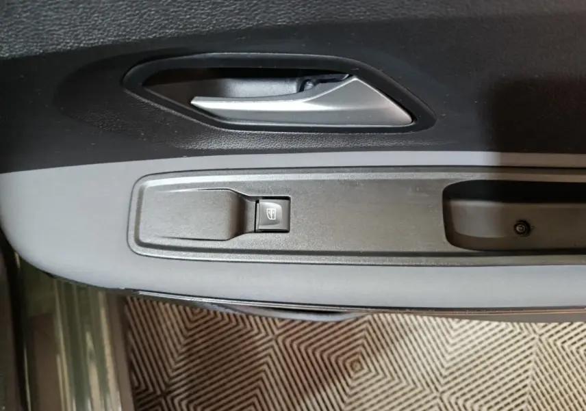 Gros plan sur la poignée intérieure et le bouton de lève-vitre côté conducteur de la Dacia Sandero Extreme+ TCe 110 verte 2024.