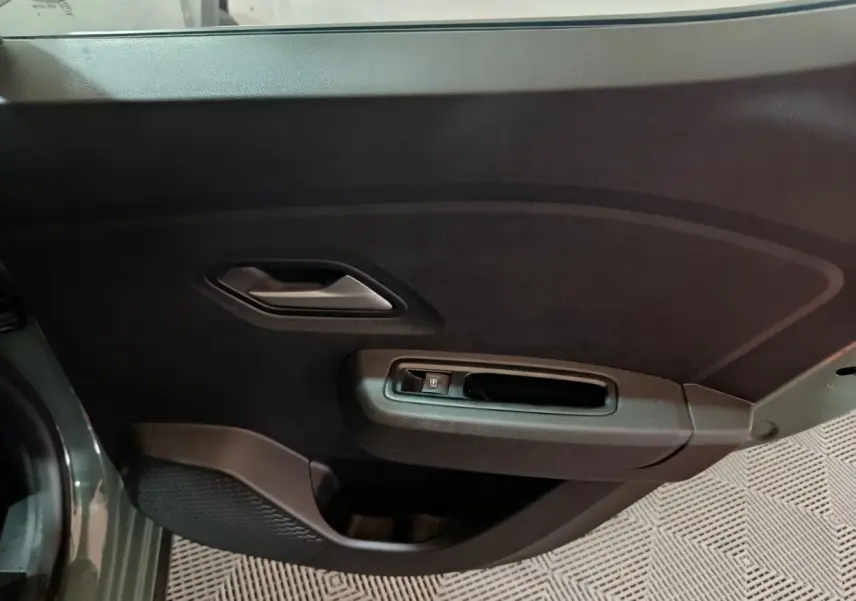 Vue rapprochée de la porte avant gauche verte de la Dacia Sandero Extreme+ TCe 110 avec poignée intérieure et commande de vitre.