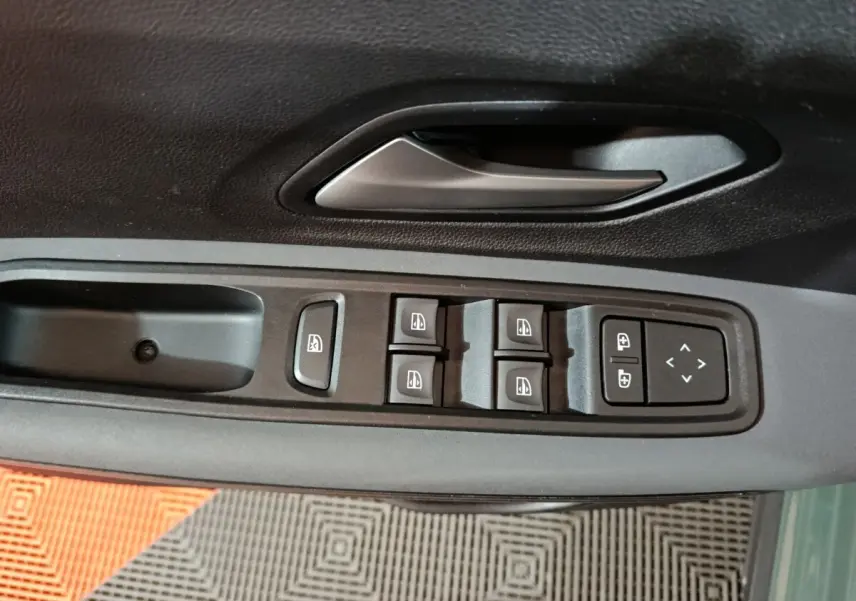 Gros plan sur la commande des vitres et rétroviseurs côté conducteur d'une Dacia Sandero vert 2024.