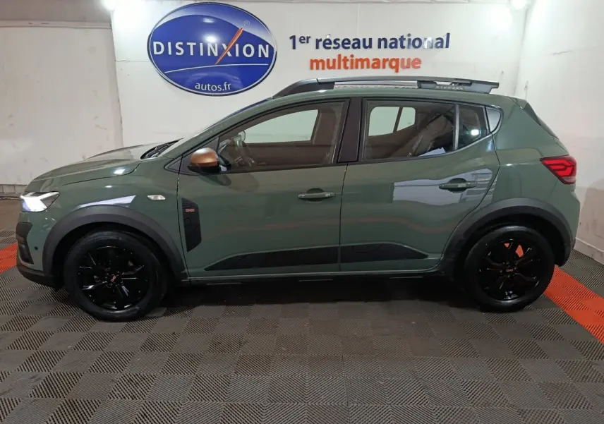 Vue de profil droit d'une Dacia Sandero Extreme+ TCe 110 2024 verte avec jantes noires et rails de toit assortis.