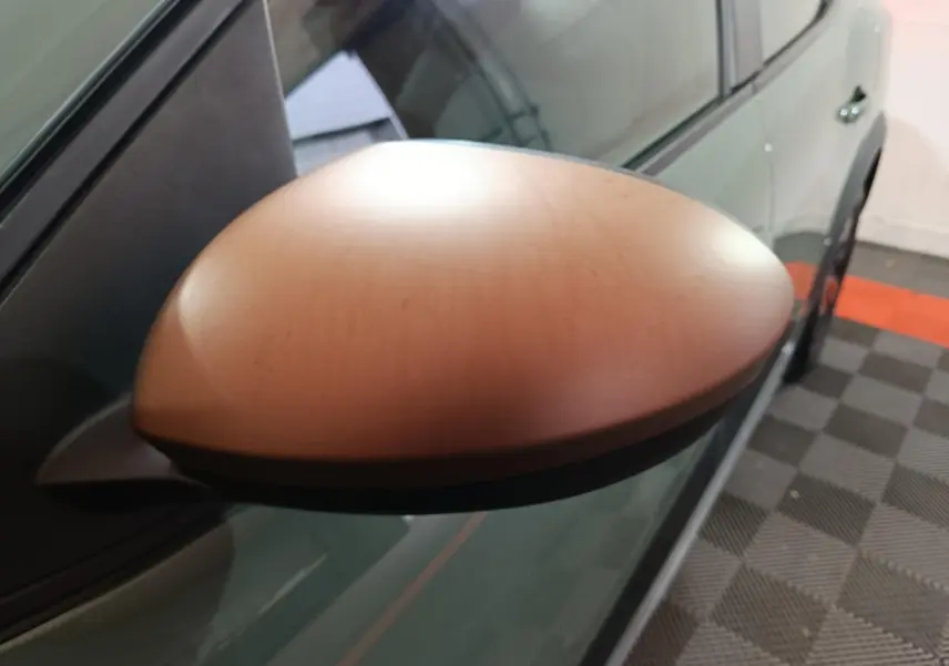 Rétroviseur droit vert métallisé de la Dacia Sandero Extreme+ 2024, vue rapprochée en intérieur sur sol damier.