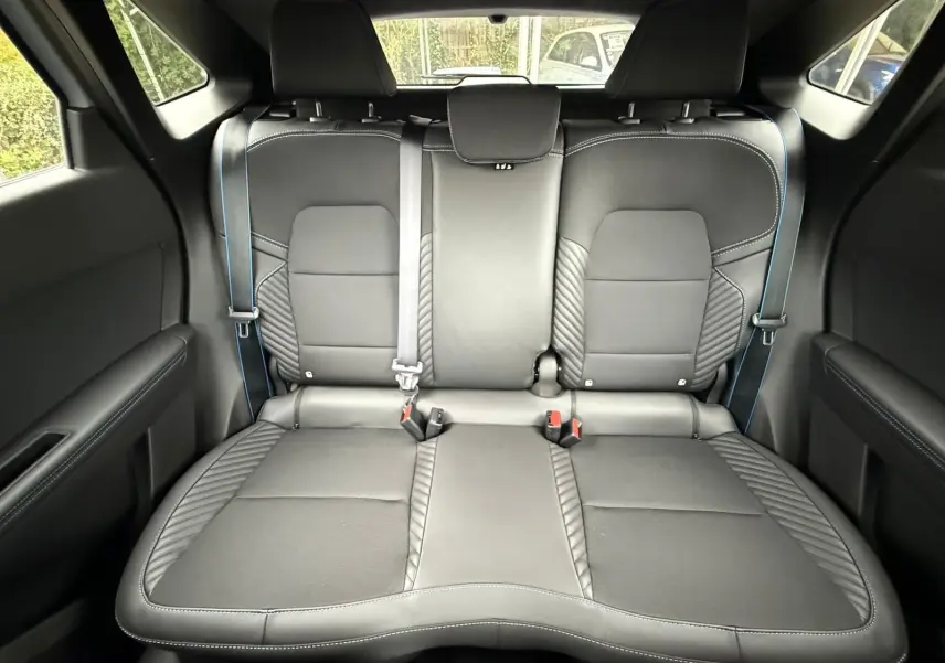 Vue intérieure arrière des sièges noirs en cuir avec surpiqûres bleues du Renault Symbioz gris Rafale 2026.