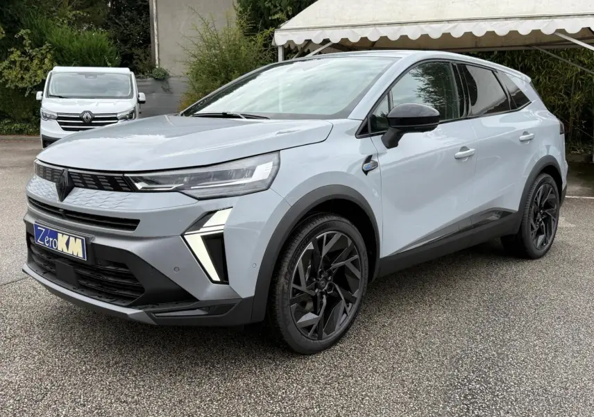 Vue 3/4 avant d’un Renault Symbioz gris rafale avec jantes noires et feux LED distinctifs, stationné sur un parking.