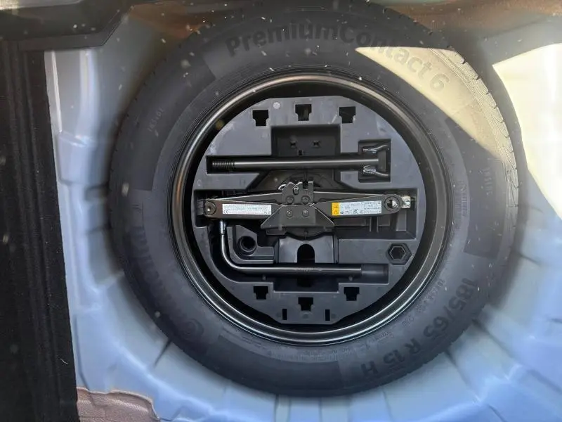 Gros plan sur la roue de secours et le cric intégrés dans le coffre d’une Renault Clio 2025 Bleu Iron.