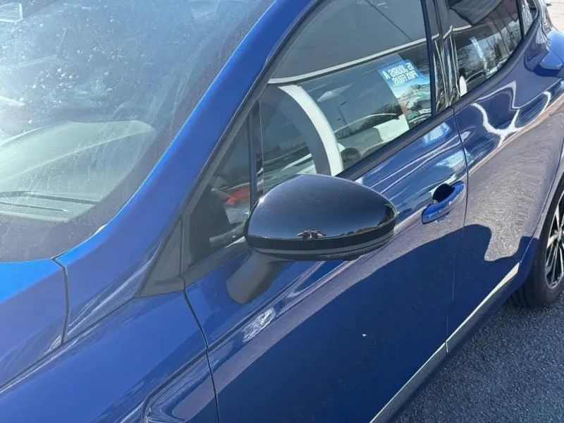 Vue rapprochée du côté gauche avant de la Renault Clio 2025 en Bleu Iron avec rétroviseur noir brillant.