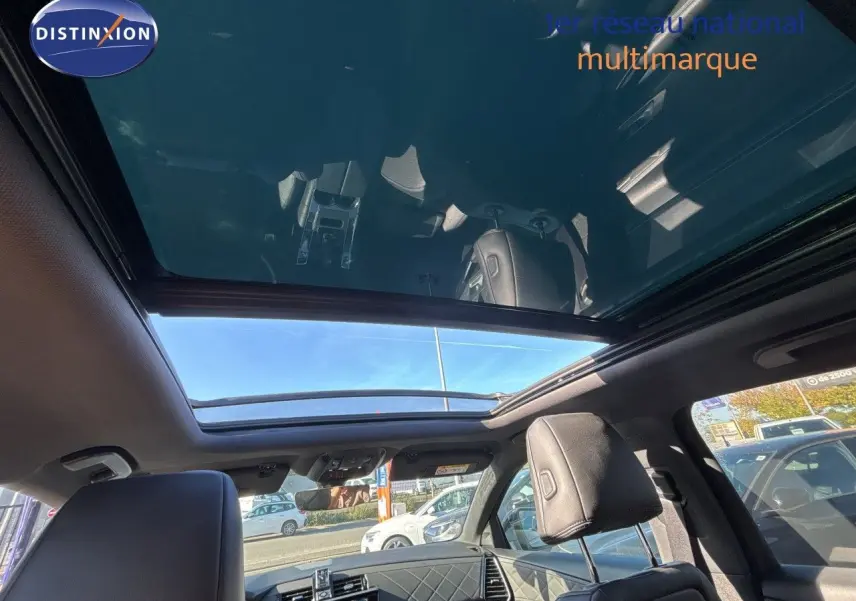 Vue intérieure du toit panoramique ouvert du DS7 Crossback E-TENSE 2021 en cuir noir, avec lumière naturelle et ciel visible.