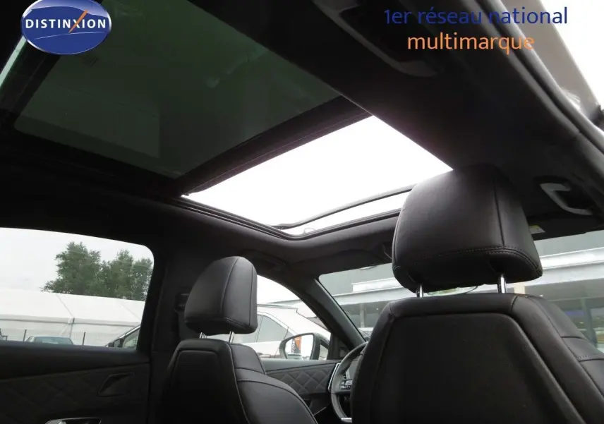 Vue intérieure du DS7 Crossback 2021 montrant les sièges avant en cuir noir et le toit panoramique ouvert.
