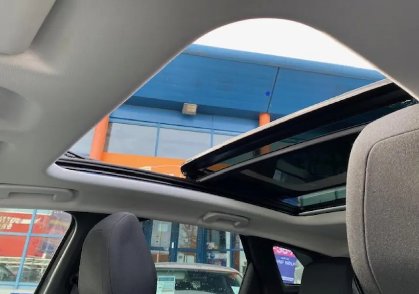 Vue intérieure du toit ouvrant panoramique ouvert sur Peugeot 3008 gris platinium, avec sièges avant en tissu gris.