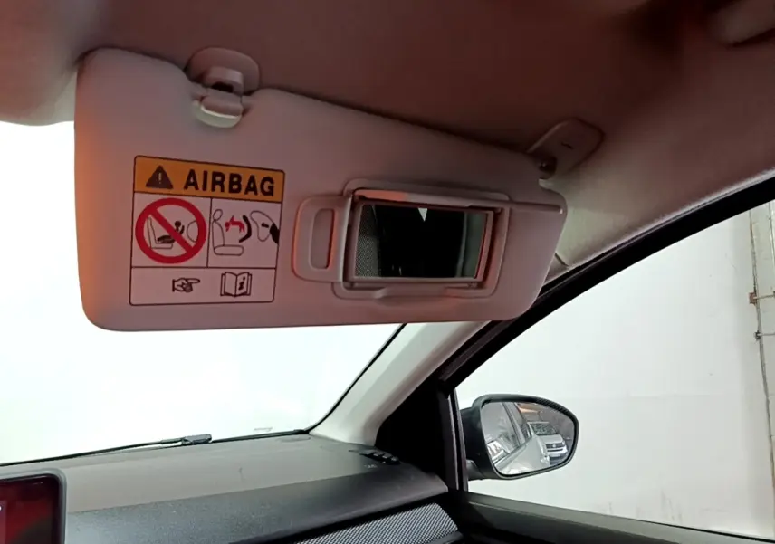 Intérieur de la Dacia Sandero blanc, vue côté passager avec pare-soleil ouvert et miroir de courtoisie visible.