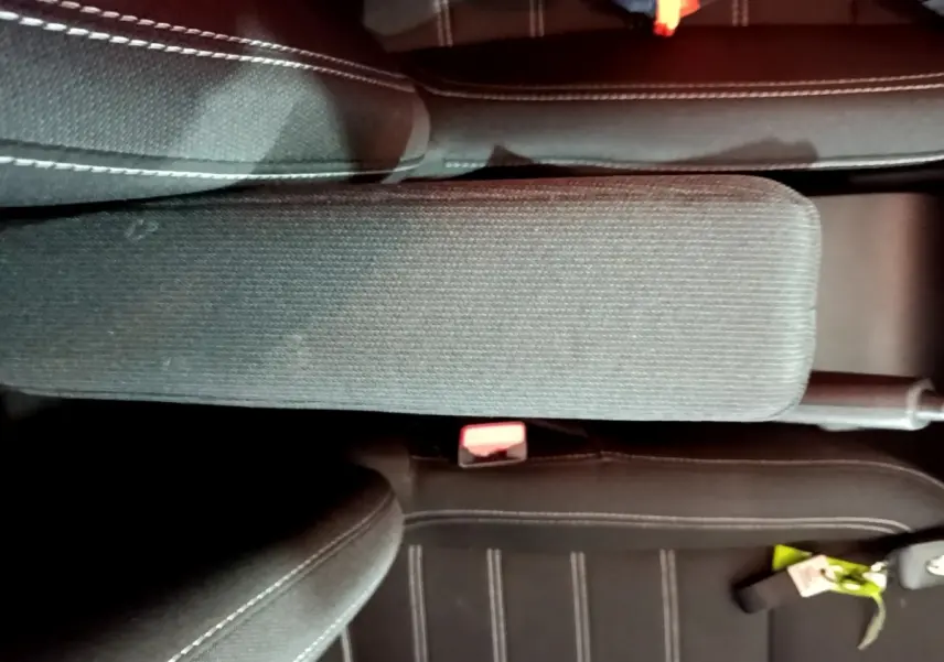 Vue rapprochée de l'accoudoir central et des sièges noirs à surpiqûres blanches de la Dacia Sandero Confort 2022.