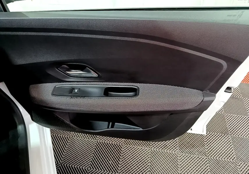 Vue intérieure de la porte avant gauche blanche d'une Dacia Sandero 2022, avec poignée argentée et habillage noir texturé.