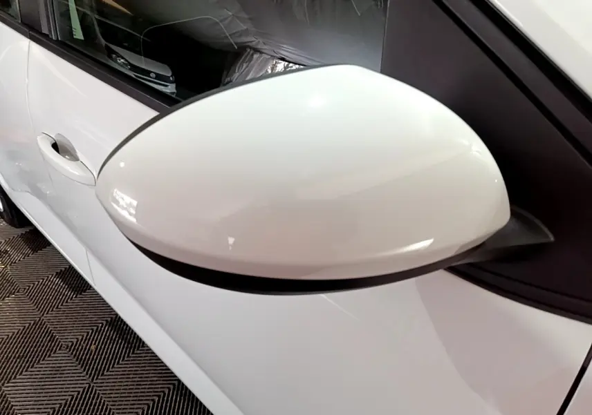 Gros plan sur le rétroviseur côté gauche blanc d'une Dacia Sandero Confort TCe 90 de 2022, carrosserie blanche visible.