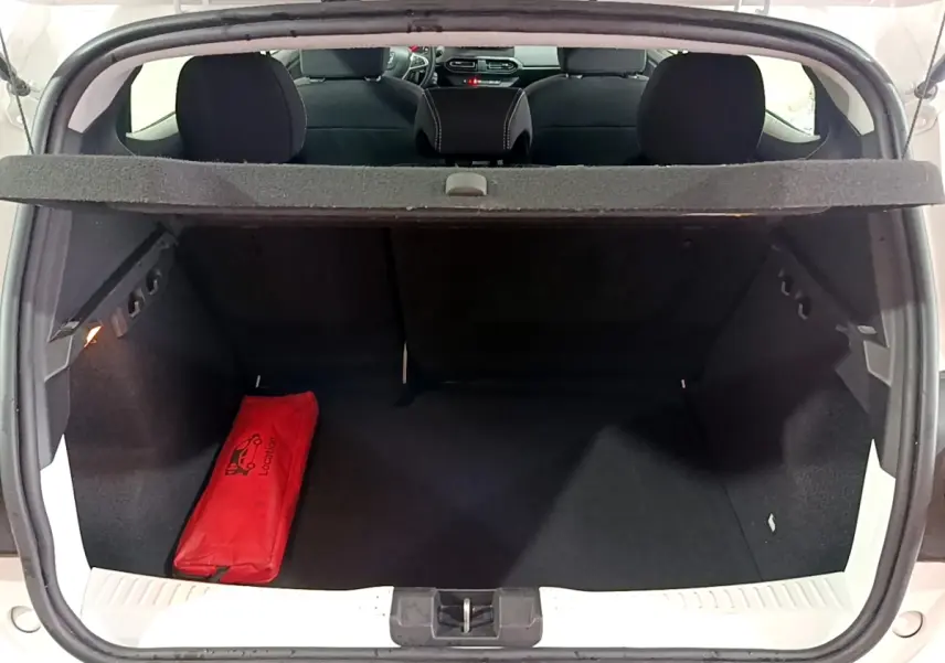 Coffre ouvert vu de l'arrière d'une Dacia Sandero blanc 2022, avec trousse de secours rouge à gauche.