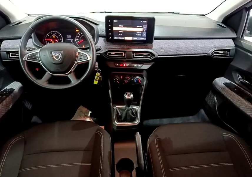 Vue intérieure avant centrée sur le tableau de bord et volant cuir synthétique de la Dacia Sandero Confort 2022.