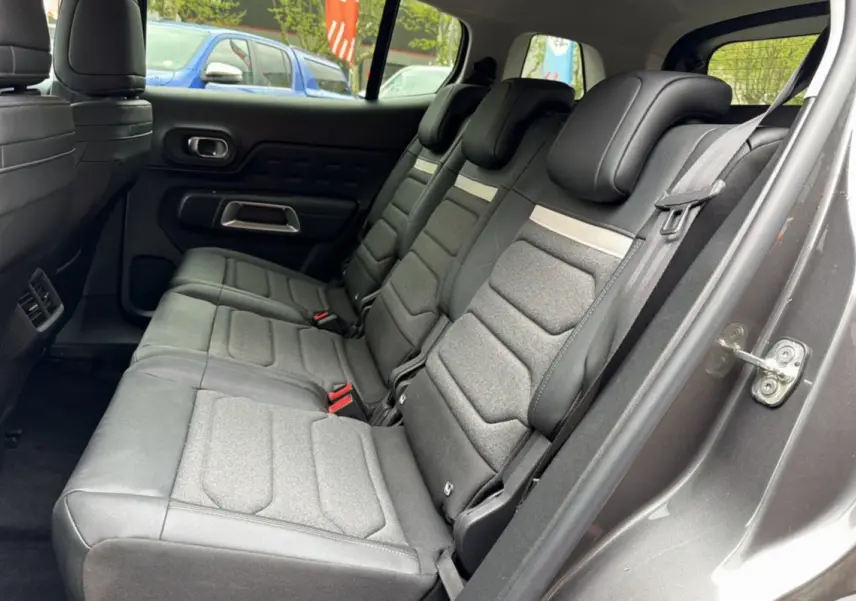 Vue latérale des trois sièges arrière individuels en tissu gris du Citroën C5 Aircross Hybrid 2025, avec portière ouverte.