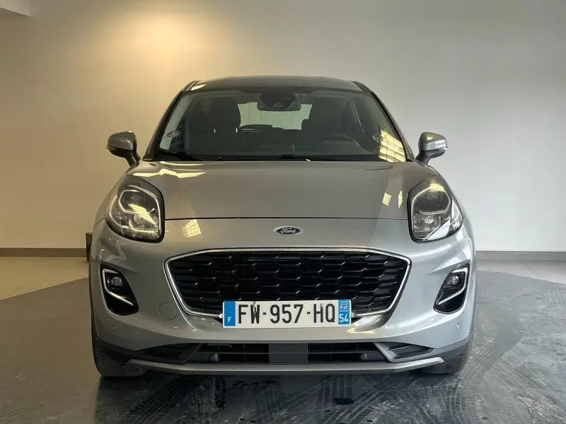 Vue frontale d'un Ford Puma gris Solar métallisé avec calandre noire et phares LED allumés dans un intérieur neutre.