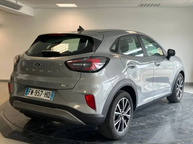 Vue 3/4 arrière droite d'un Ford Puma gris Solar métallisé avec jantes alu et becquet arrière en intérieur showroom.