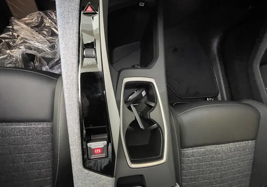 Vue plongeante sur la console centrale du Peugeot 3008 noir, avec porte-gobelets et frein à main électrique éclairé.