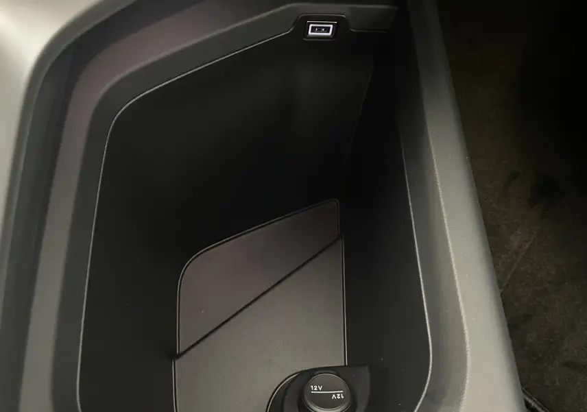 Vue rapprochée de la console centrale noire du Peugeot 3008 2025, montrant une prise USB et une prise 12V.