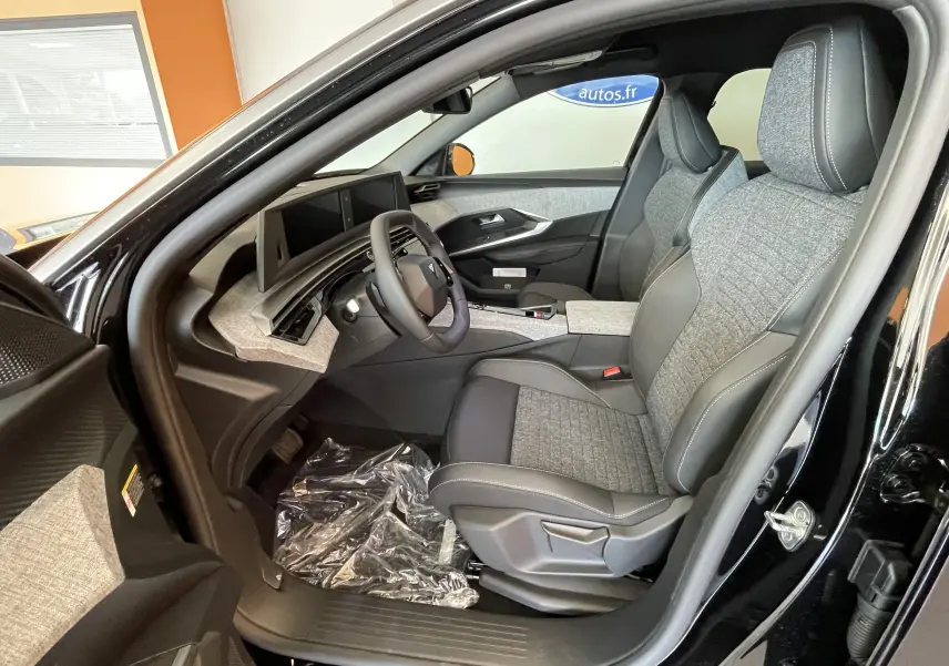 Intérieur côté conducteur du Peugeot 3008 noir 2025, sellerie tissu gris et tableau de bord avec double écran HD flottant.