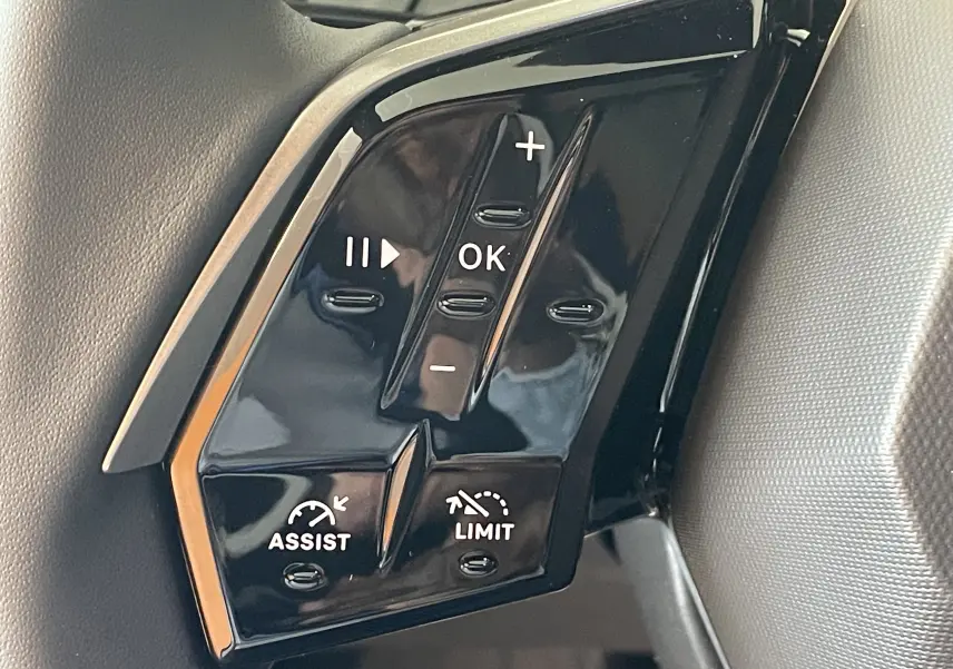 Gros plan sur les commandes au volant noir brillant du Peugeot 3008 NV Hybrid 136 Allure, boutons de régulateur et limiteur.