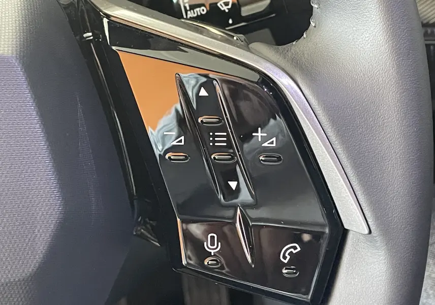 Gros plan sur les commandes vocales et téléphone sur le volant noir du Peugeot 3008 NV Hybrid 2025.