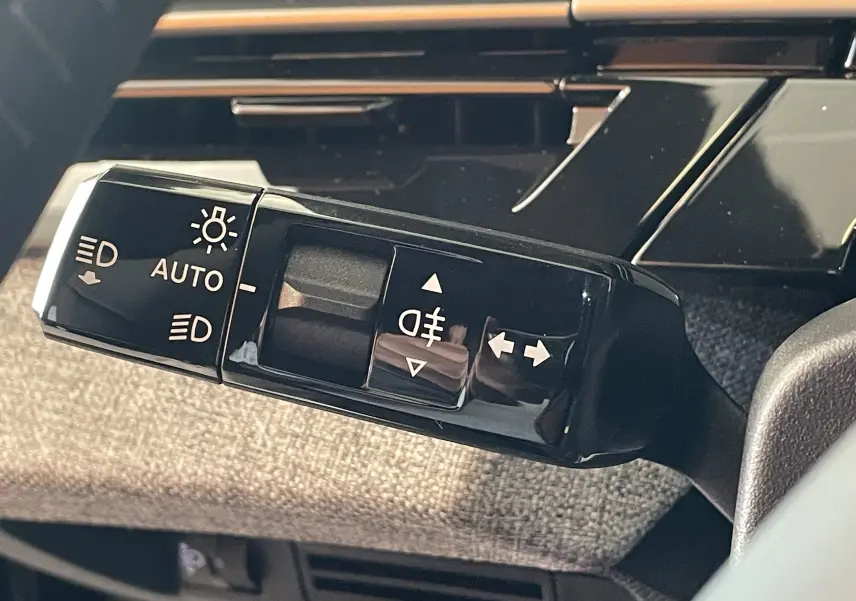 Gros plan sur la commande des feux et clignotants dans l'habitacle du Peugeot 3008 noir 2025.