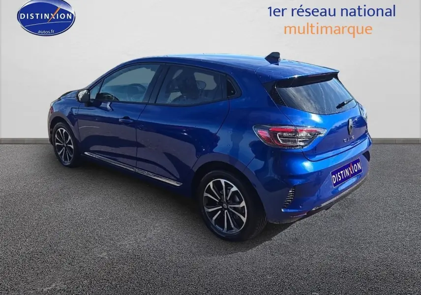 Renault Clio V bleu iron vue 3/4 arrière côté gauche, avec jantes alu et becquet arrière noir.