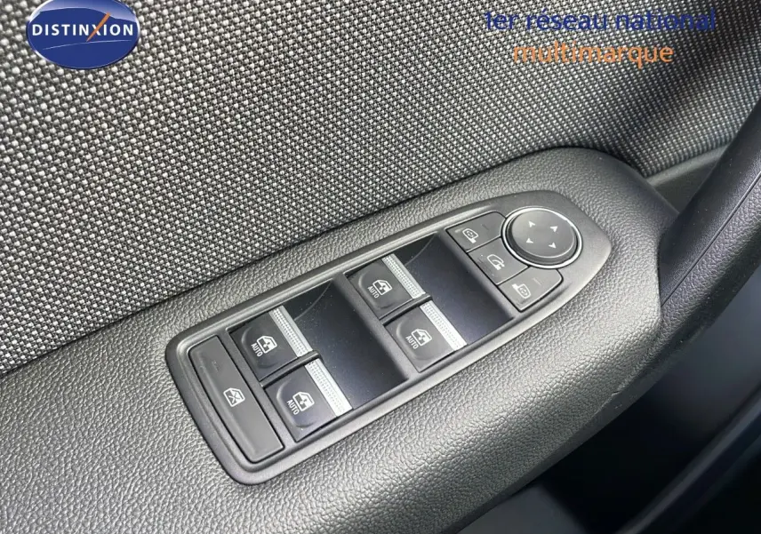 Gros plan sur les commandes des vitres électriques et réglage des rétroviseurs sur la porte intérieure d'un Renault Captur rouge 2025.